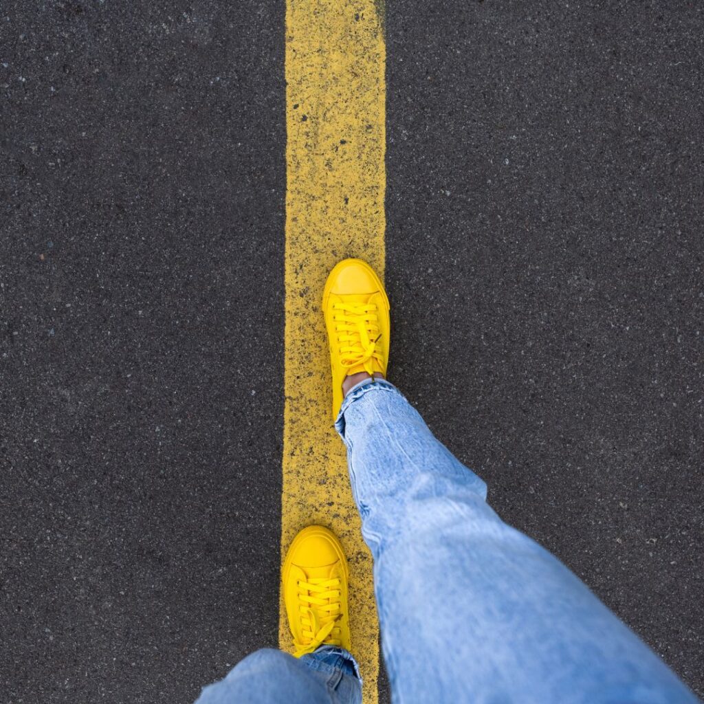 A person with yellow shoes walking on a yellow line